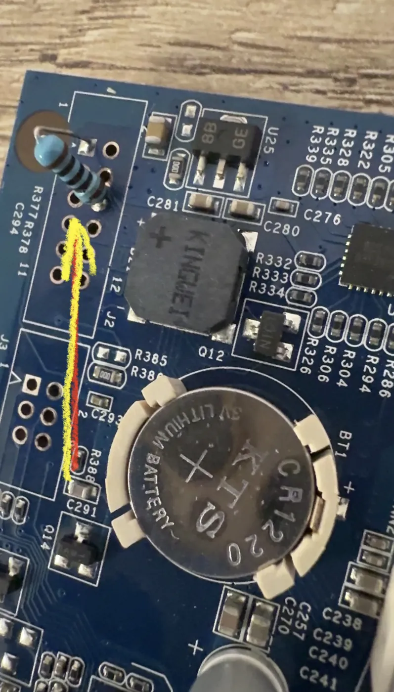 Synology RS815+ motherboard with a new 100 ohm resistor soldered in and a yellow arrow marking the spot by the CR1220 battery